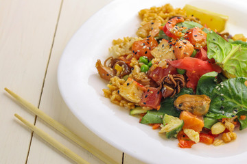 Plate with boiled rice, vegetables and seafood on table, close up