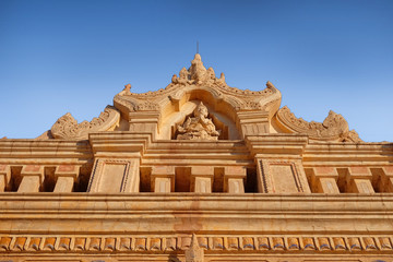 Obraz premium Blue sky above an ancient temple carved with religious motifs in old Bagan, Myanmar.