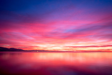 Fototapeta na wymiar dark violet clouds with orange sun light and pink light in wonderful twilight sky on lake Bodensee in Lindau