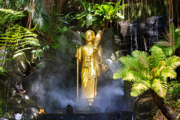 Golden Buddha statue in the tropical garden in Wat Saket Golden Mountain Temple in Bangkok,...