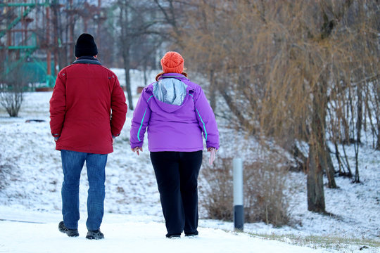 Fat Couple Walking Down In Winter Park. Man And Overweight Woman On A Street, Concept Of Healthy Lifestyle