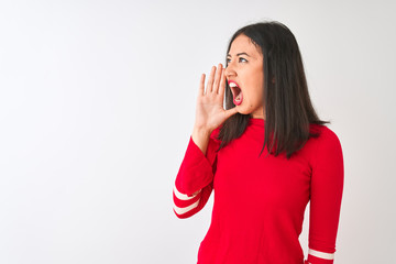 Young beautiful chinese woman wearing red dress standing over isolated white background shouting and screaming loud to side with hand on mouth. Communication concept.