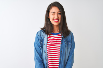 Young chinese woman wearing striped t-shirt and denim shirt over isolated white background winking...