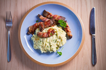 Beef liver wrapped in bacon with mash potato on blue table. Overhead horizontal image