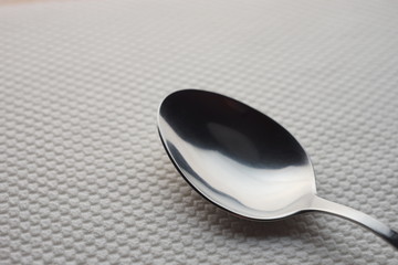 modern silver stainless steel spoon on a table with a white tablecloth.