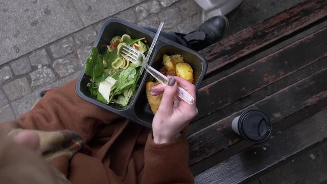 woman eating a satad on city beanch
