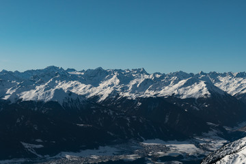 Snowy alpine mountain range on a clear sunny day during a winter morning