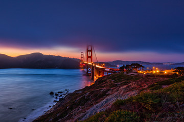 Fototapeta na wymiar The fog lifts above the Golden Gate Bridge after the sun has set along the San Francisco shoreline