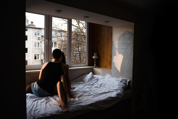 Silhouette on the wall of couple in love, who lie on the bed at home, tenderly hug each other, kiss. Morning of the newlyweds at the window. The lovers spend the weekend together. Concept of tactility