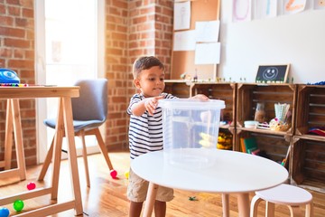 Beautiful toddler boy playing with plastic basket at kindergarten