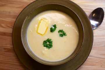 Creamy cauliflower soup with cream and butter is decorated with decorative parsley leaves. Modern Norwegian food.