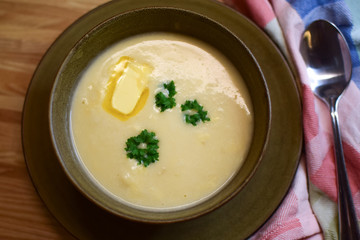 Creamy cauliflower soup with cream and butter is decorated with decorative parsley leaves. Modern Norwegian food.