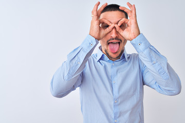 Young handsome business man standing over isolated background doing ok gesture like binoculars sticking tongue out, eyes looking through fingers. Crazy expression.