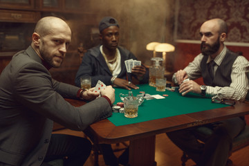 Poker players with cards playing in casino