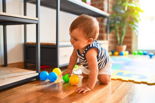 Adorable toddler crawling around lots of toys at kindergarten