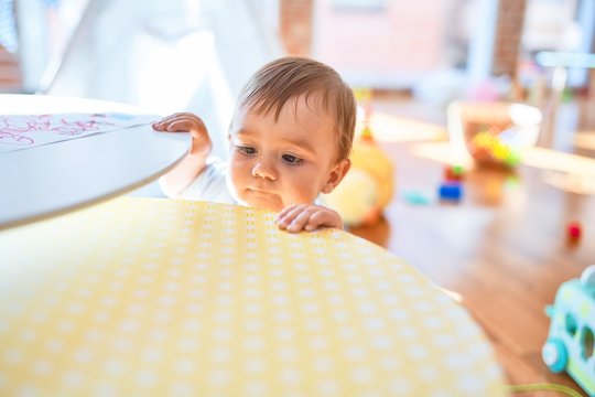 Adorable toddler standing around lots of toys at kindergarten