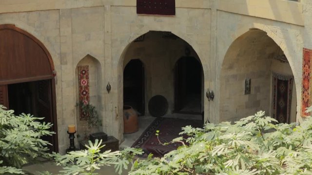 The courtyard of the old city in Baku. Oriental decoration and architecture. Panorama of balconies and a view of the curb on which a large oriental carpet dries