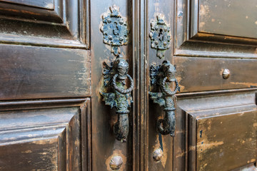 Seahorse shaped door handles on old brown wooden door in Lisbon, Portugal
