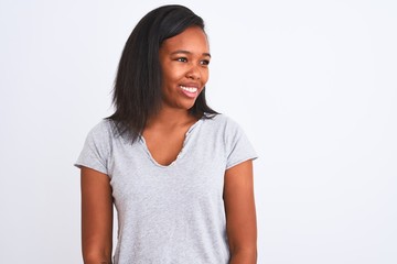 Beautiful young african american woman wearing casual t-shirt over isolated background looking away to side with smile on face, natural expression. Laughing confident.