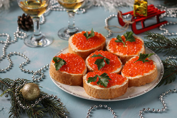 Sandwiches with red caviar are located on a plate against a light blue background, Festive snack, horizontal orientation