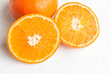Orange, ripe citrus fruits and round slice on white textured background