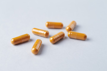 Turmeric capsules. Bright paper background. Close up. 