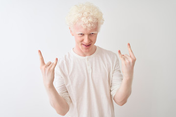 Young albino blond man wearing casual t-shirt standing over isolated white background shouting with crazy expression doing rock symbol with hands up. Music star. Heavy concept.