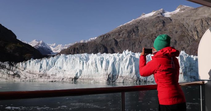 Alaska cruise ship passenger woman photographing glacier in Glacier Bay National Park, USA. Tourist taking photo picture using smartphone on travel vacation. Margerie Glacier.