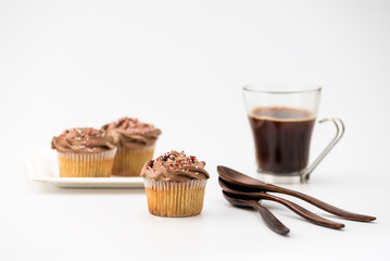 Chocolate muffins on a white background with a cup of coffee and wooden spoons. Homemade baking, Selective focus, close up.