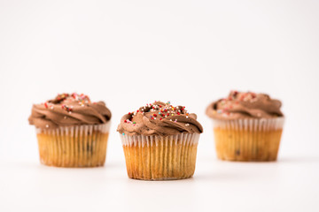 Delicious chocolate muffins, isolated on white background. Muffin and paper, sweet food or unhealthy eating theme.