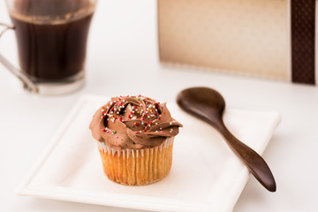 Chocolate muffins on a white background with a cup of coffee and wooden spoon. Homemade baking, Selective focus, close up.
