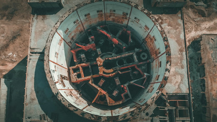 Aerial top view of abandoned and ruined Nuclear Power Plant. Large industrial construction with round tower of atomic reactor, post-apocalypse and world war concept, drone shot.