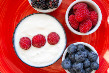 yogurt with whole fresh blueberries raspberries on wooden table. Healthy eating