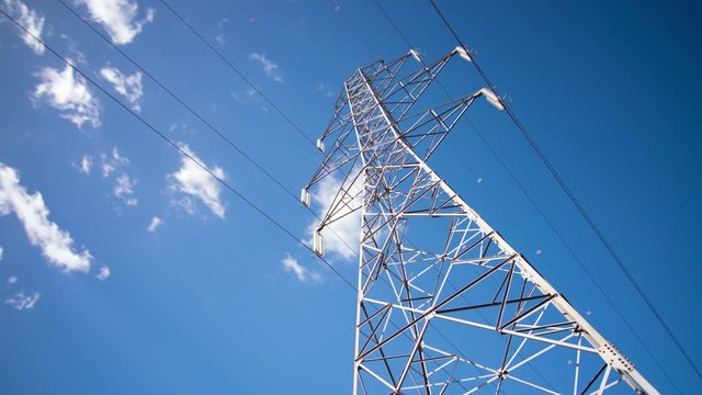 Looking up at tall electrical pylon and blue sky, low angle, timelapse