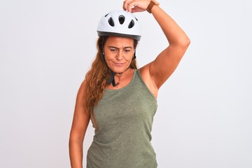 Middle age mature cyclist woman wearing safety helmet over isolated background confuse and wondering about question. Uncertain with doubt, thinking with hand on head. Pensive concept.