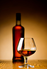 A glass of cognac and bottle in the background