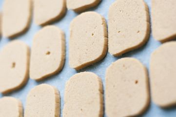 Preparation for baking cookies. An even row of rectangular raw cookie dough on baking parchment. Close-up. Selective focus