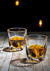 View of two filled whiskey glasses on a wooden bar top