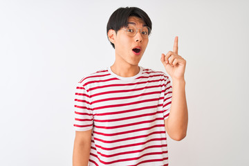 Young chinese man wearing glasses and striped t-shirt standing over isolated white background pointing finger up with successful idea. Exited and happy. Number one.