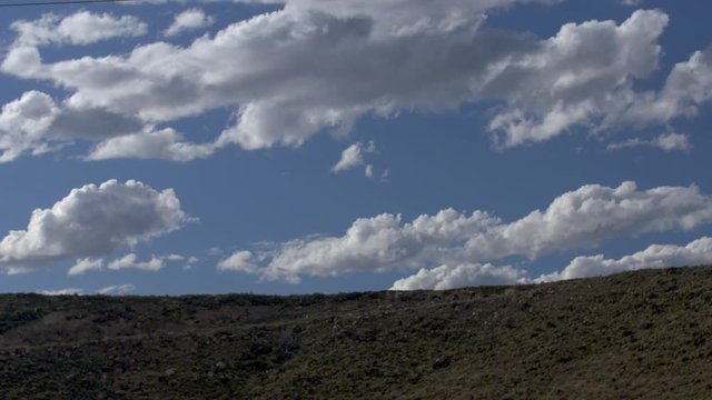 Beautiful time-lapse of clouds in cobalt blue sky along desert ridge in southwest U.S. 