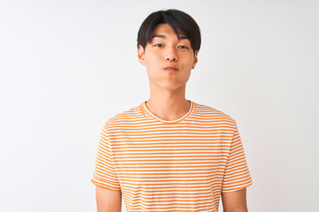 Young chinese man wearing casual striped t-shirt standing over isolated white background puffing cheeks with funny face. Mouth inflated with air, crazy expression.