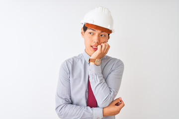Chinese architect man wearing tie and helmet standing over isolated white background looking stressed and nervous with hands on mouth biting nails. Anxiety problem.