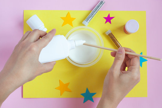 Making slime toy at home. Girls hands add ingredients to homemade DIY slime or handgum. Flat lay, top view.