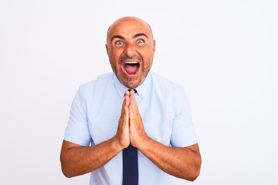 Middle age businessman wearing tie standing over isolated white background praying with hands together asking for forgiveness smiling confident.