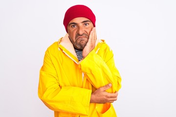 Middle age man wearing rain coat and woolen hat standing over isolated white background thinking looking tired and bored with depression problems with crossed arms.