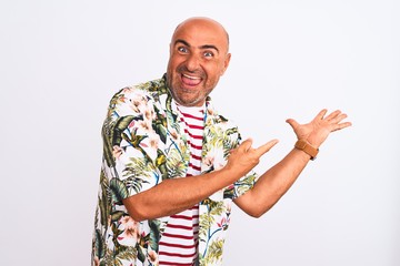 Fototapeta premium Middle age handsome man on holiday wearing summer shirt over isolated white background amazed and smiling to the camera while presenting with hand and pointing with finger.