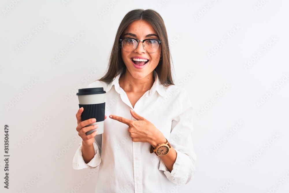 Wall mural Young businesswoman wearing glasses drinking coffee over isolated white background very happy pointing with hand and finger