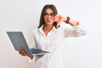 Beautiful businesswoman wearing glasses using laptop over isolated white background with angry...
