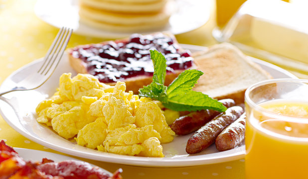breakfast with scrambled eggs, sausage links and toast.