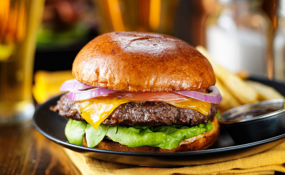 cheeseburger and fries on plate served with beer at restaurant